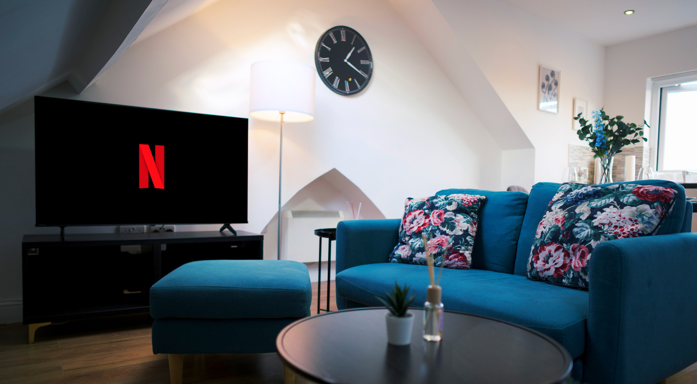Blue sofa and patterned cushions beneath a sloping ceiling and skylight.