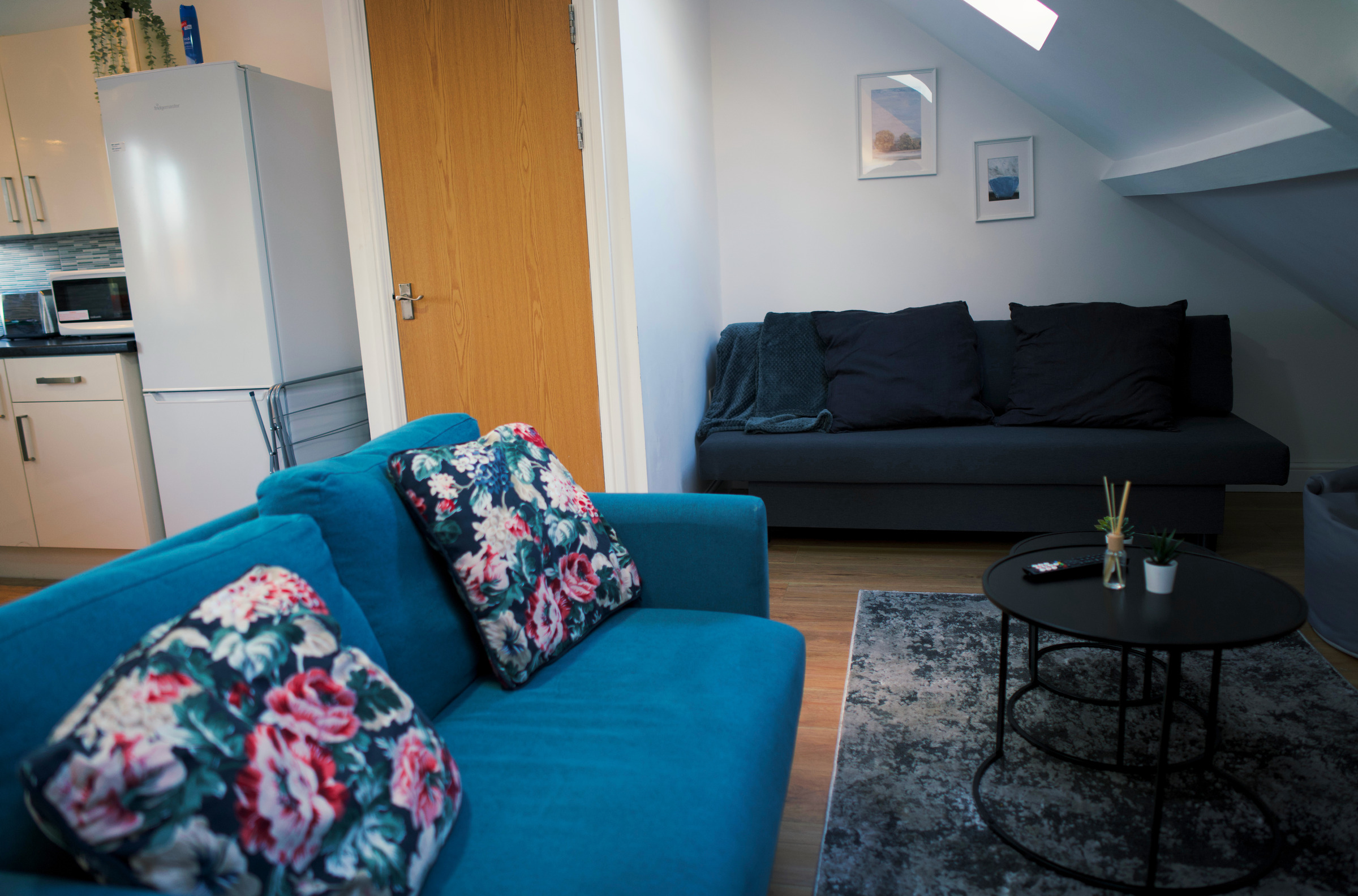 Blue patterned sofa and low round tables in the apartment living space.