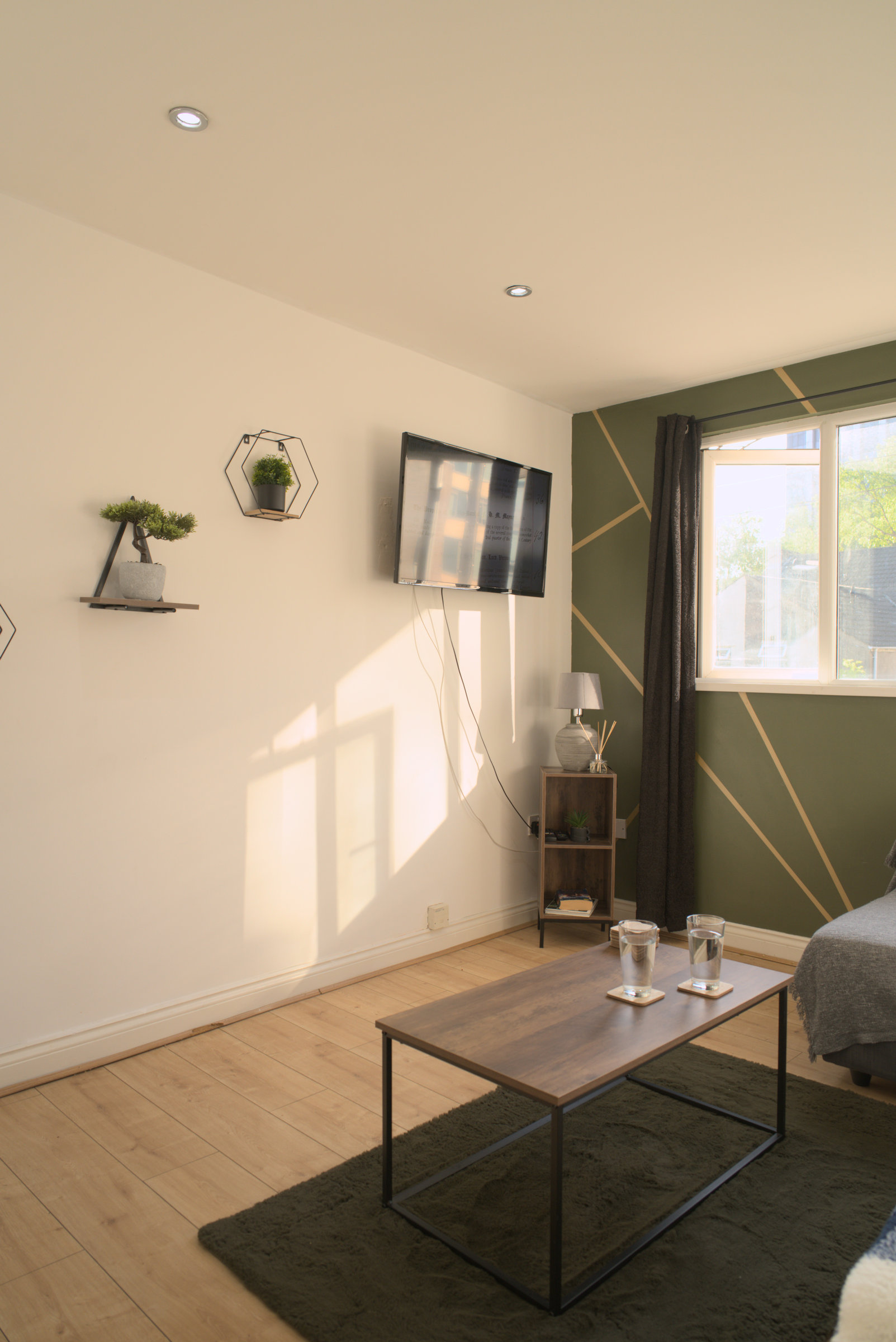 A second view of an olive living room, showing its window, sofa and coffee table.