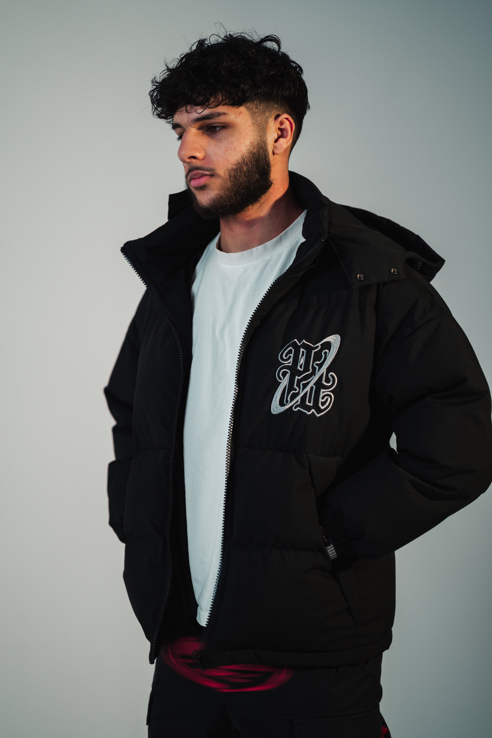 A model wearing a black embroidered puffer jacket against a pale studio background.