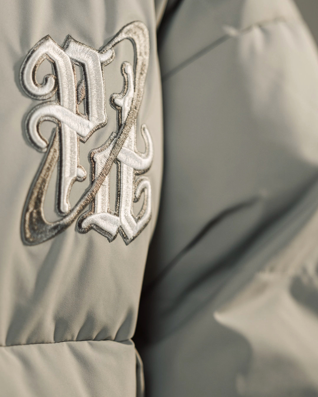 Raised embroidered lettering on a puffer jacket from a studio fashion film.