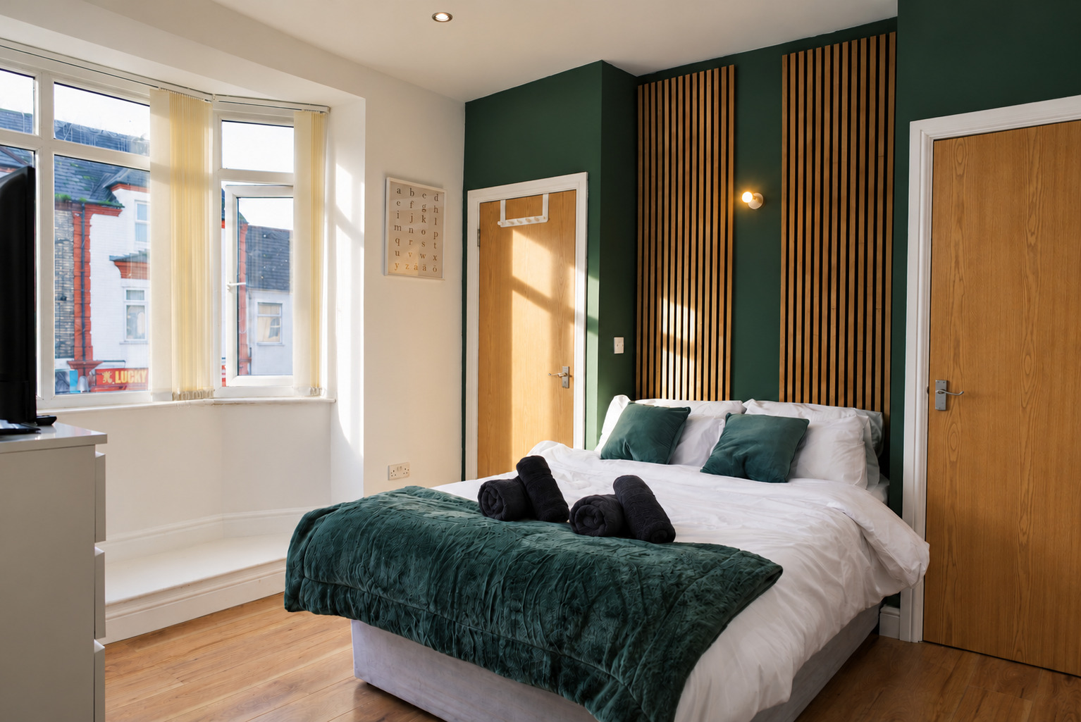 Sunlight across green velvet bed linen, timber wall slats and the actual street-facing window.