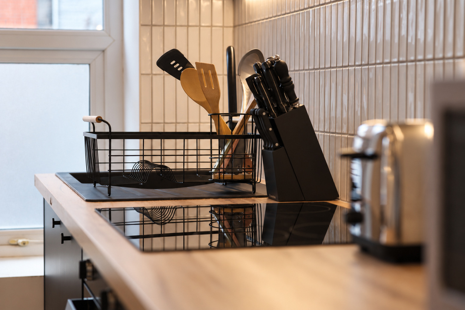 Utensils and a knife block on the kitchen worktop beside the sink.