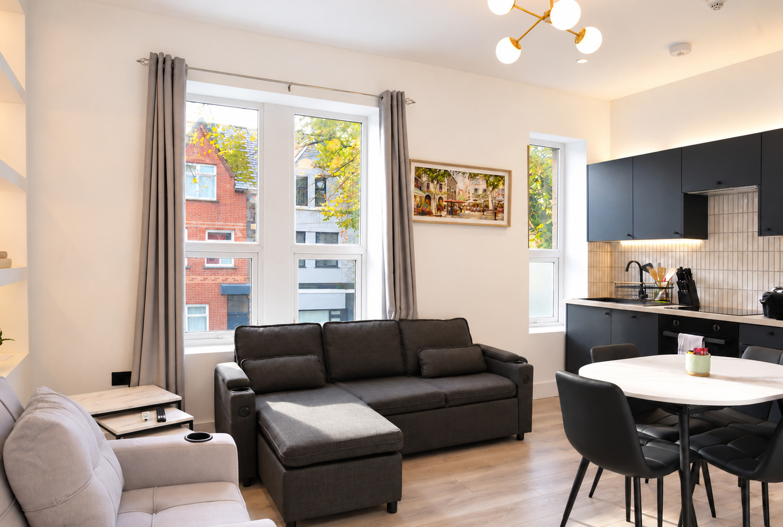 Black corner sofa, dining table and fitted kitchen connected in one living space.