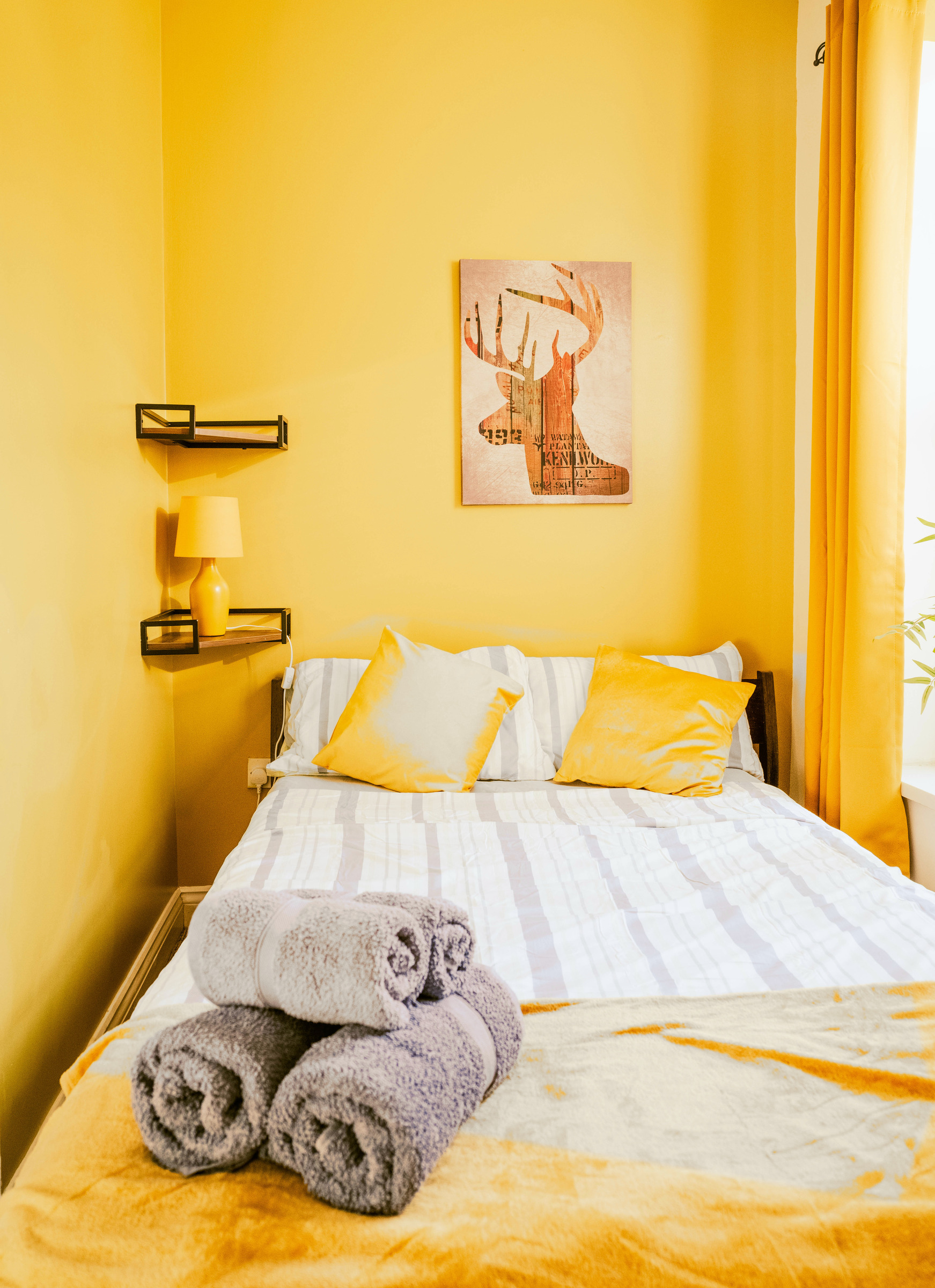 Mustard bed linen and neatly rolled towels in the yellow guest bedroom.