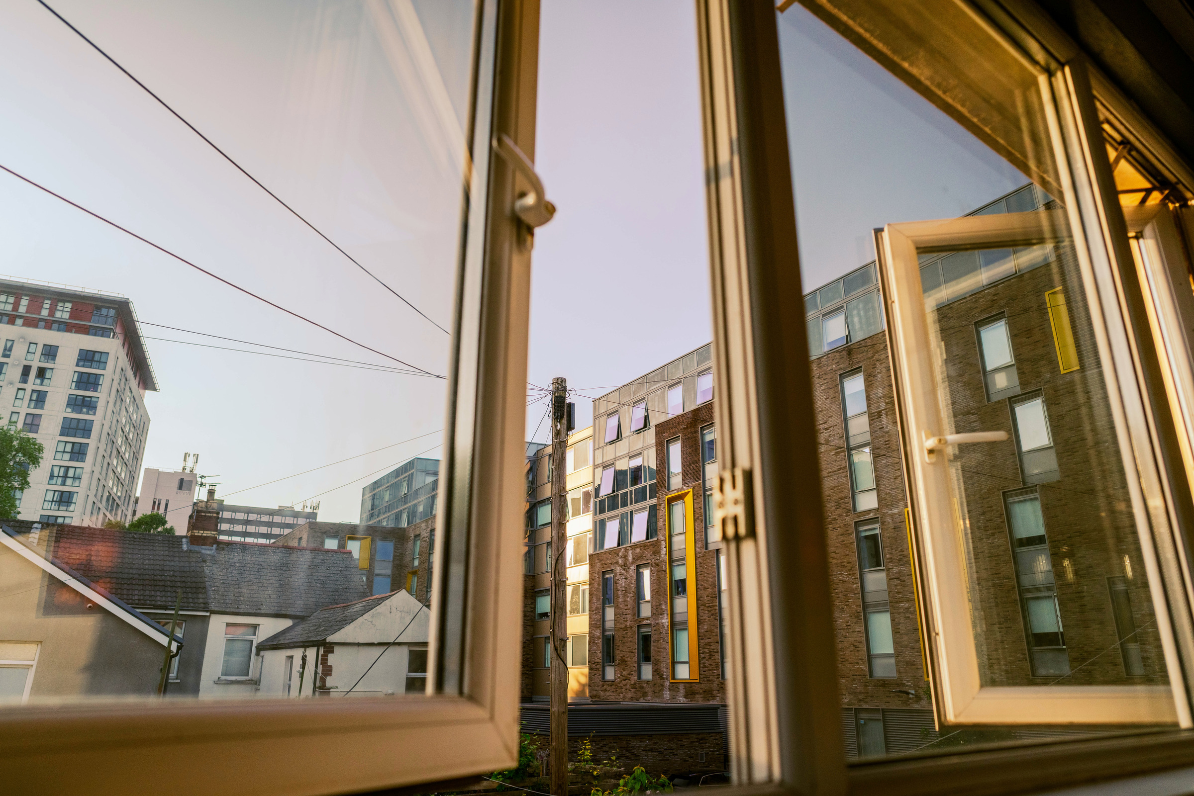 The photographed neighbouring rooftops and buildings through an open apartment window.