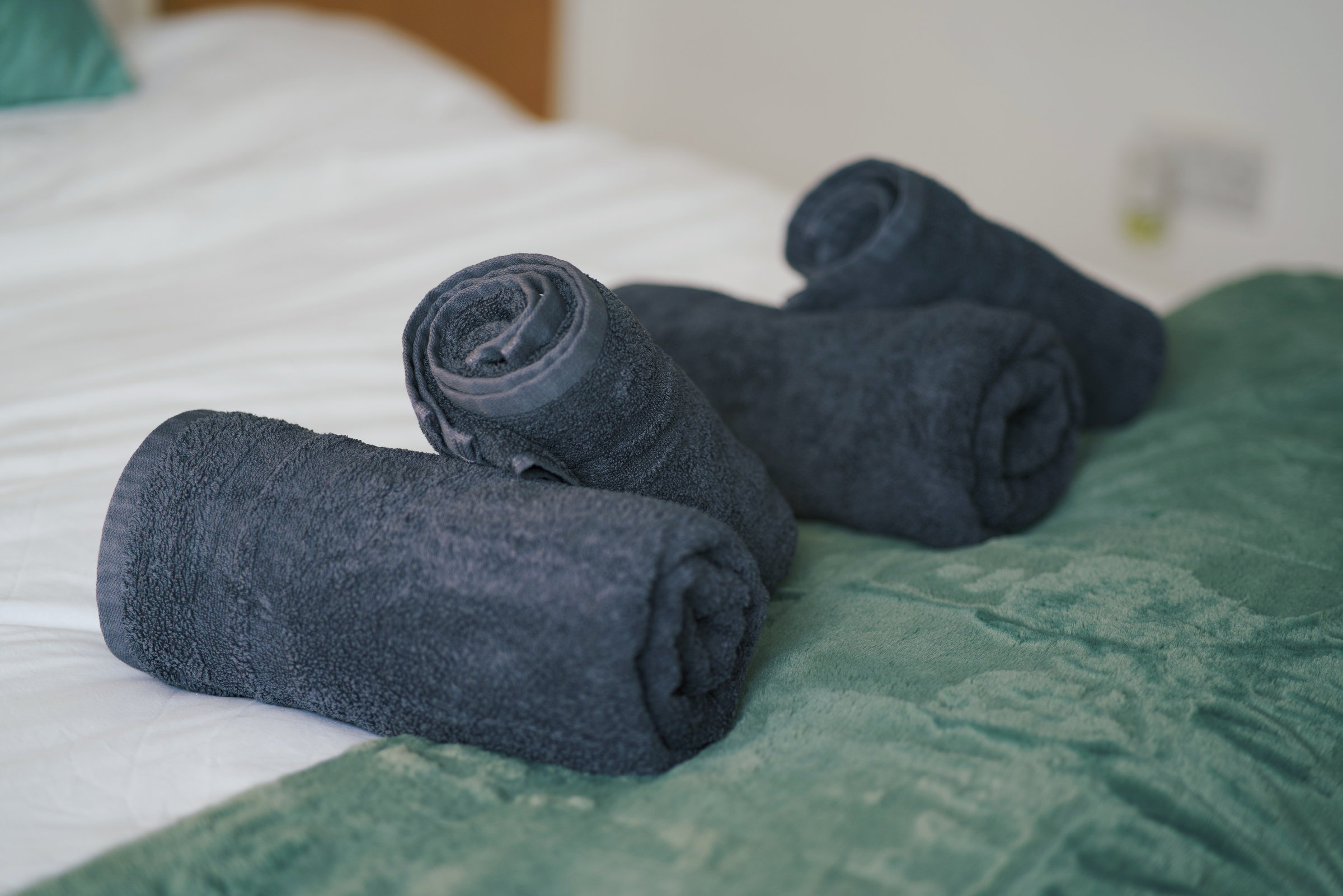 Two dark towel animals on textured green velvet bed linen.