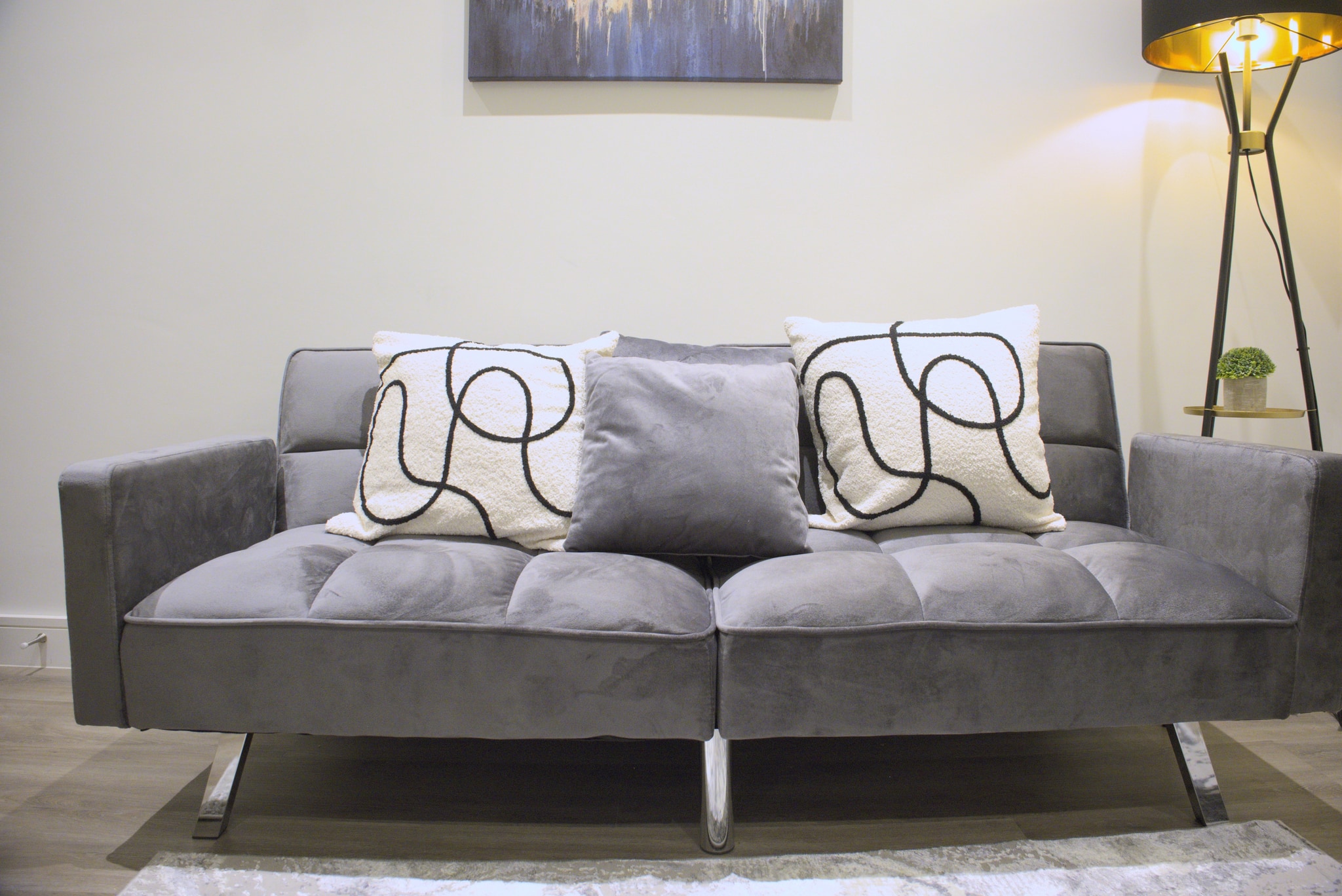 After: The identical sofa photograph after exposure and colour correction, with the same furniture, cushions and framing.